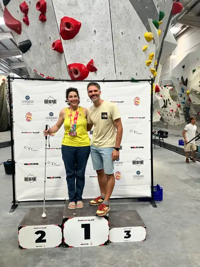 Two people on a climbing gym podium holding their medals